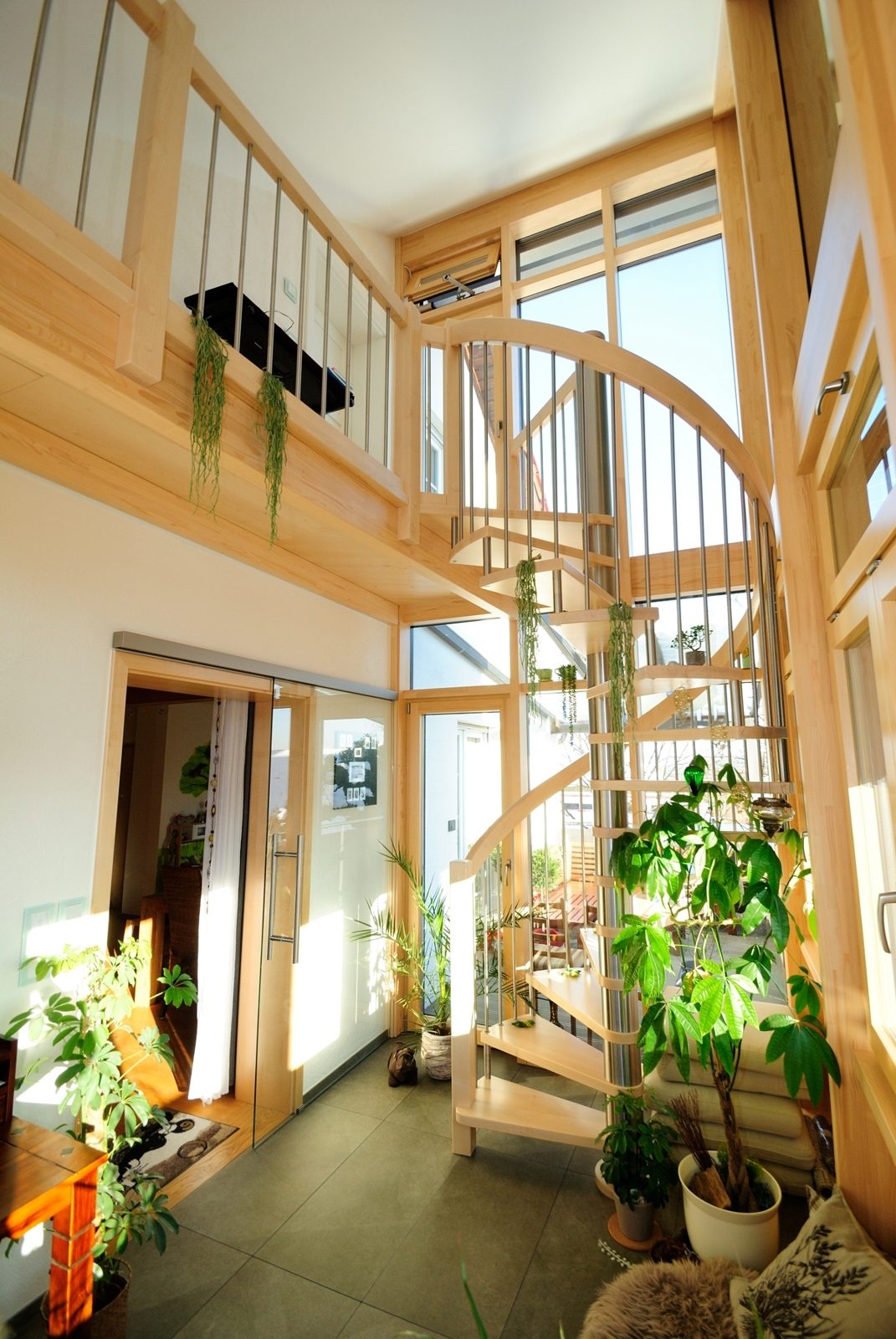 Wohnhaus-Innenausbau von Schreinerei Jürgen Mayer: gewendelte Holztreppe in lichtdurchflutetem Treppenhaus